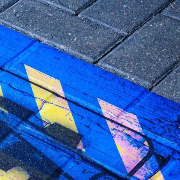 M15-M MaxGRAB adhesive floor print vinyl for exterior flooring signs and promotional graphics has been printed with yellow chevrons onto a blue background with a cracking pattern design and applied to exterior block brick work.