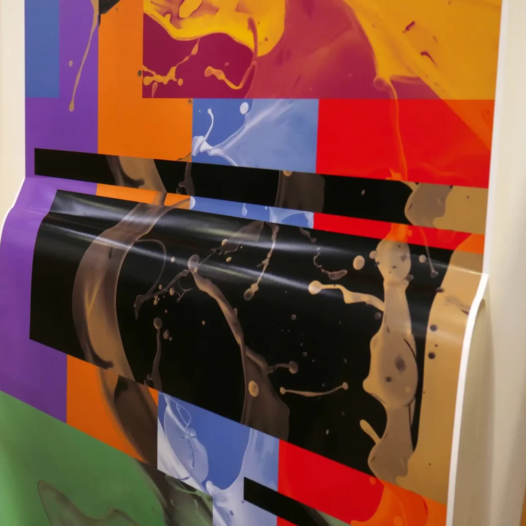 M15-P-P monomeric matt white self-adhesive print vinyl with a colourful, decorative abstract printed design is half-applied to a flat surface with the liner hanging down away from the adhesive side of the film but remains attached at the bottom of the film prior to it being completely removed and fully stuck in position onto the substrate.