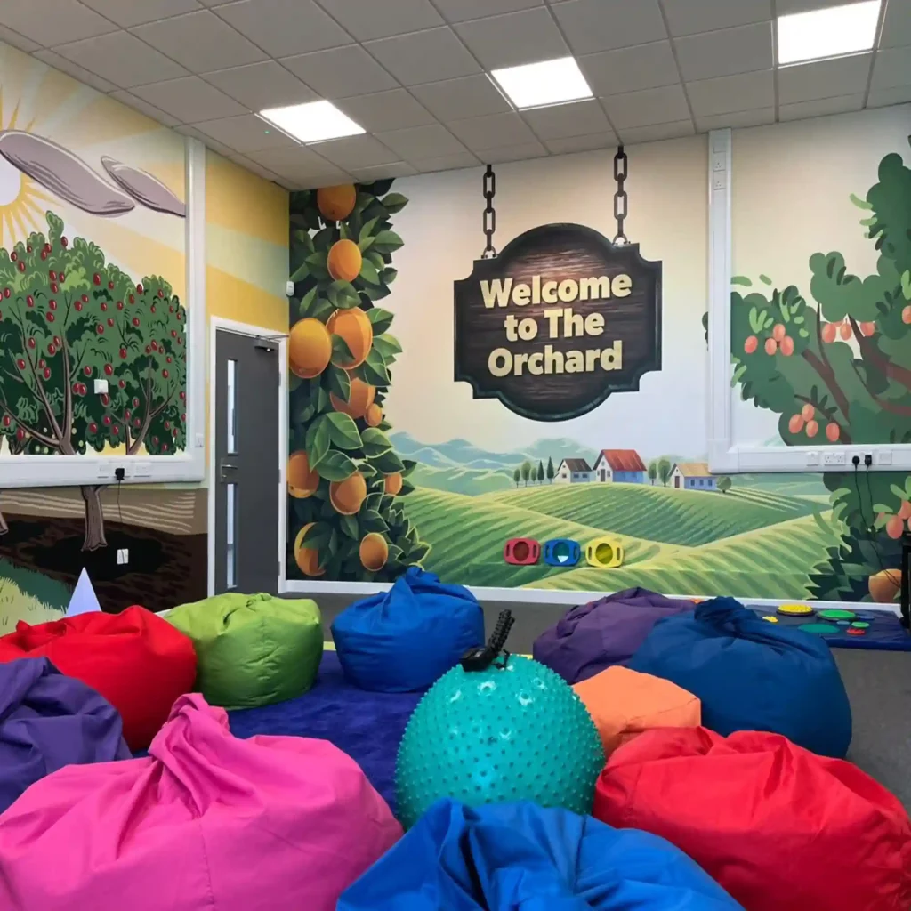 M16-H-P high opacity high-grab print vinyl, with a PE liner for added stability on digital printers, has been applied to the interior walls of this nursery classroom, adding colourful fun graphics of wide open fields and an orchard with red apples in full fruit. In the foreground are multiple bean bags in different shapes and sizes, which match the colourful room decoration.
