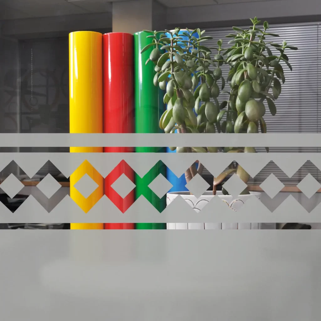 M63-W Frosted Glass etch-effect window privacy vinyl has been plotter-cut and weeded out with an interesting Aztec style, decorative geometric pattern at the top of the window with a larger, solid sheet of the silver/grey film applied below that, providing privacy for the internal office space behind the window.