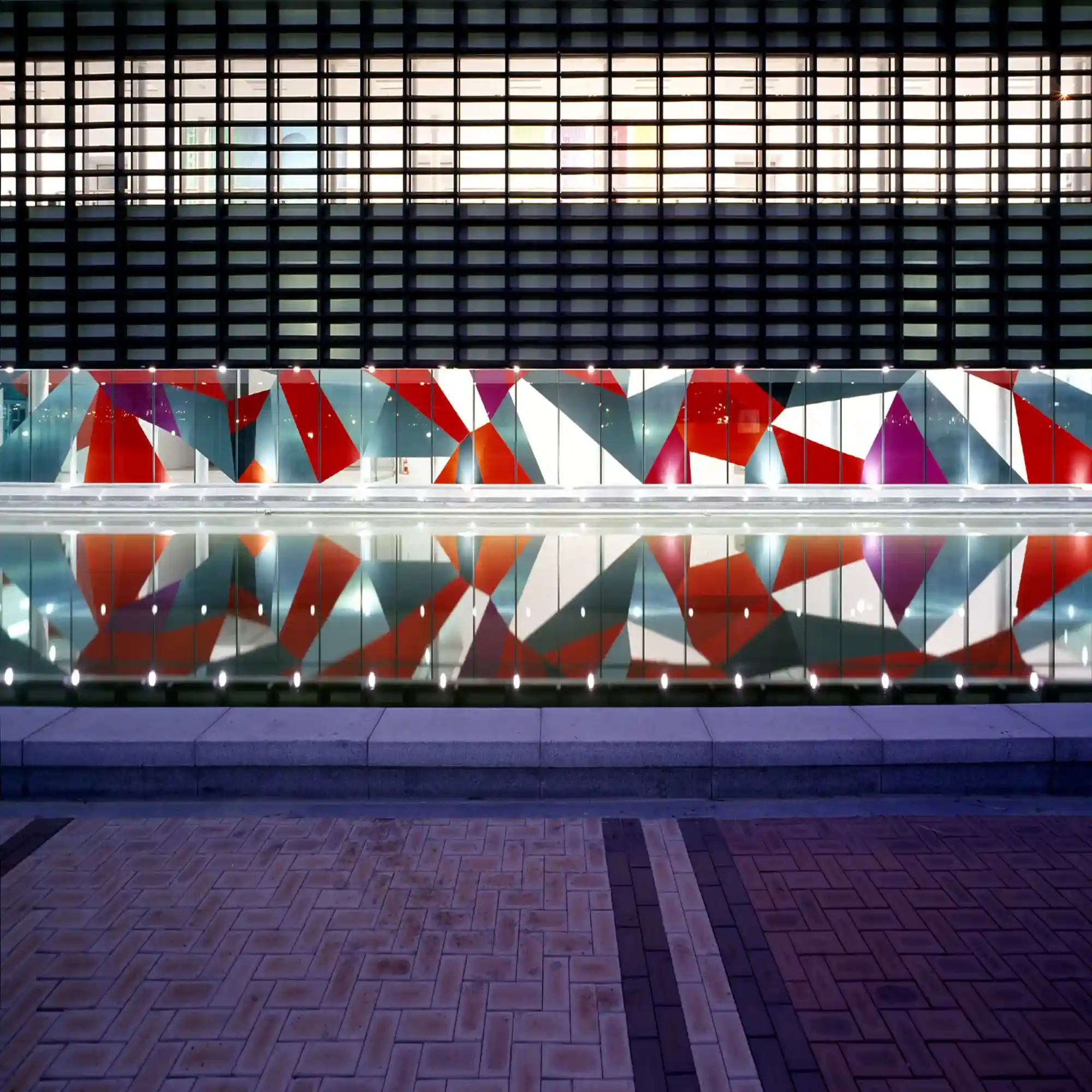 MACal 8900 self-adhesive sign vinyls from Mactac have been used here to decorate the outside windows of a large art museum with a colourful, bright, abstract pattern that is superbly reflected in the water that is out front in the large public area.