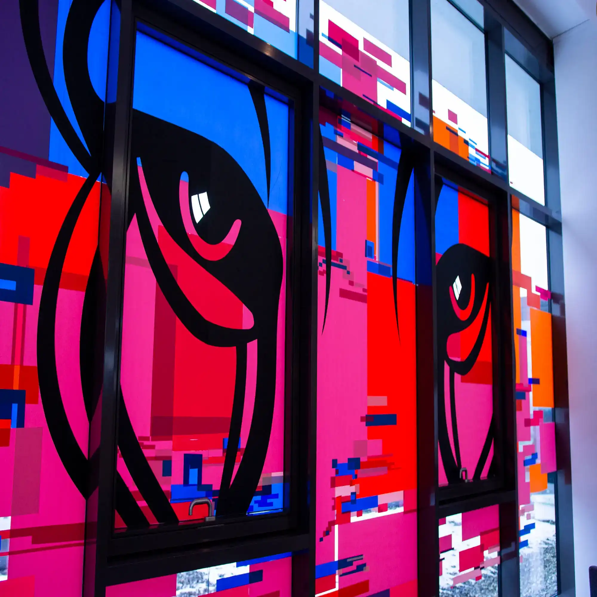 Tape Over Art in Berlin using Mactac's MACal 8900 coloured self-adhesive PVC films have been applied to a window with light from outside brightly backlighting the coloured vinyls that have been arranged and cut to create an abstract Puma cat design.
