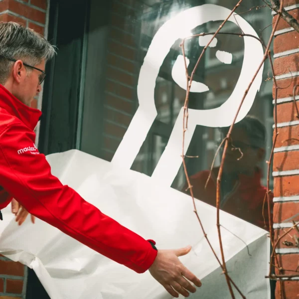 Peeling away application tape from the MACal 9200 gloss white vinyl decal sign graphic that has been positioned and applied onto a window.
