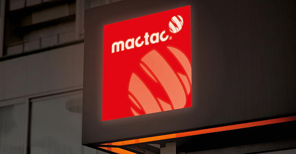 Illuminated backlit sign on building frontage in night light using Mactac 9798-30 and 9798-60 white diffuser film vinyls to block out 30% and 60% of the backlight, creating an interesting effect by screening out only a percentage of the light.