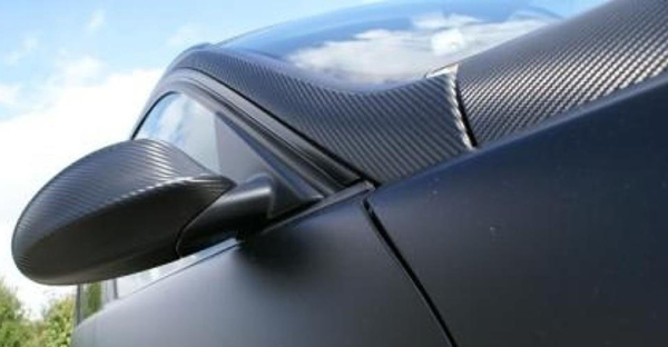 Satin Black Carbon Fibre vinyl wrap conformed over car wing morror and bonnet detail.