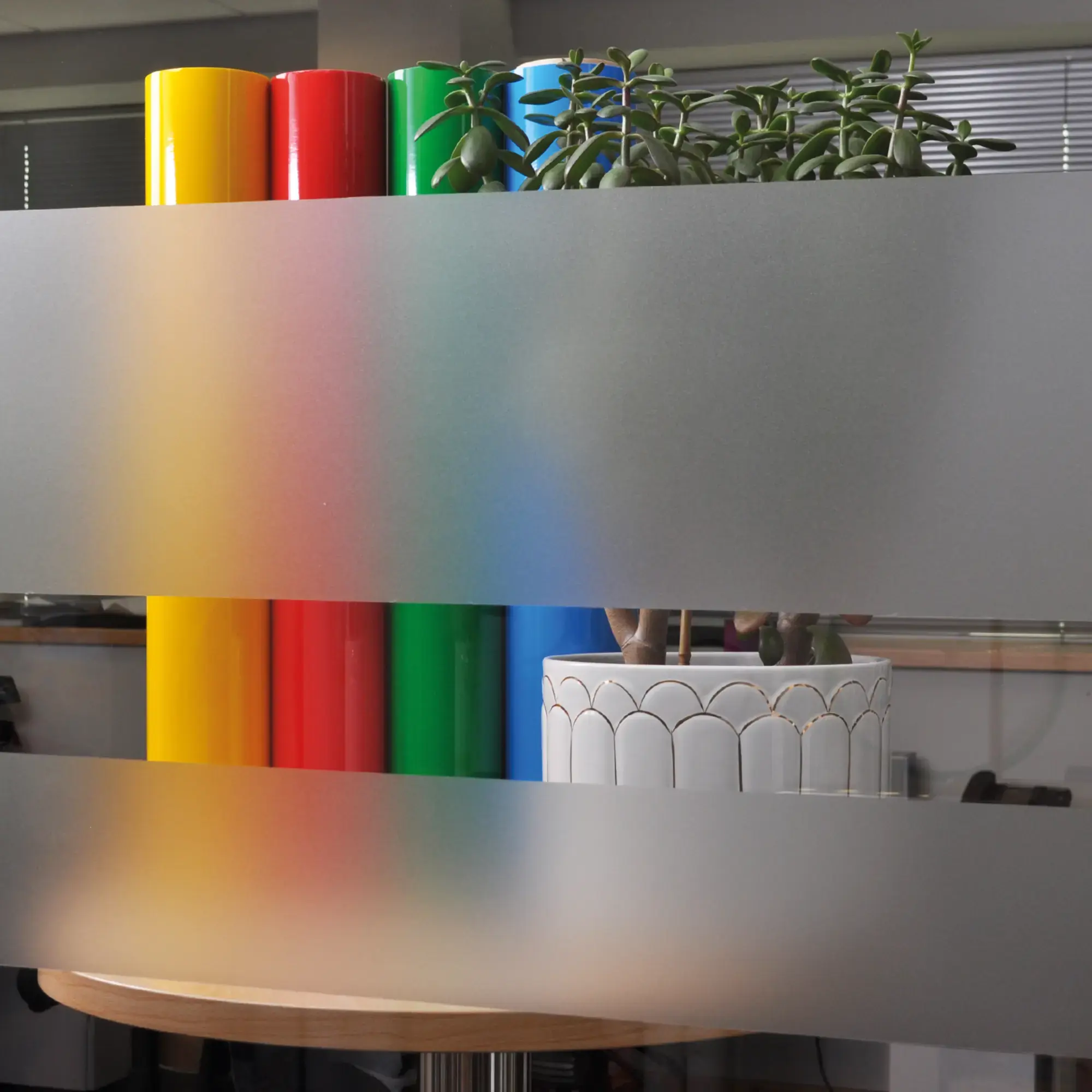 Mactac 598-03 Frosted glass window film is applied to an internal office window to show the privacy of the self-adhesive frost effect vinyl with the obscurity it offers being good with only vague colours and shapes visible of the items that are behind the film.