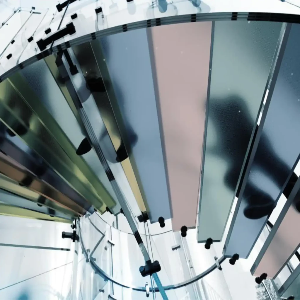 Mactac 700 Tints range of self-adhesive vinyls for window deocration and colour transformation have been used here with all the different colours from the series decorating the steps of a spiral glass staircase in a rainbow of colour, viewed from below looking upwards as people in shadow walk up the stairs, showing how the film offers resonable obscurity while allowing lots of light thorugh the films and provides a pretty spectrum of pastel like translucent colours.