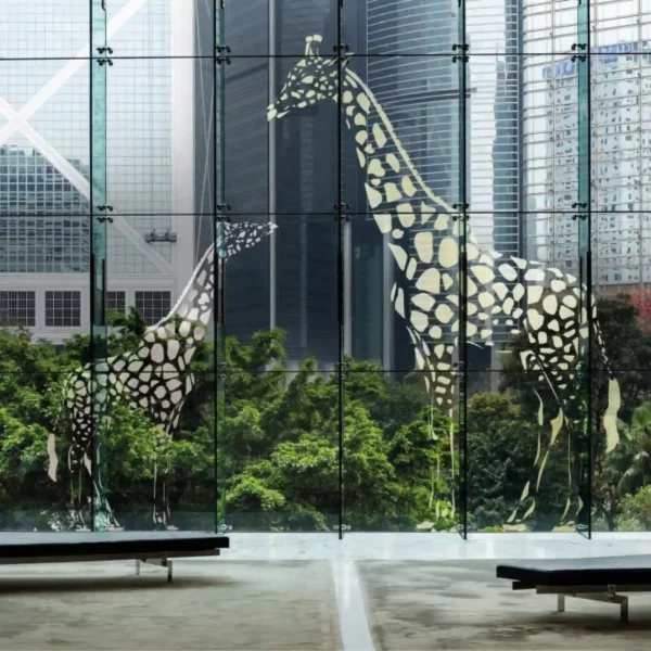 Mactac 700 Tint coloured graphics vinyl has been applied to a very large lobby window using cut-vinyl shapes to create the image of a young Giraffe looking up at a larger parent Giraffe providing a light and airy window decoration with low shrubbery on the outside of the room providing an organic feel to the finished interior space.