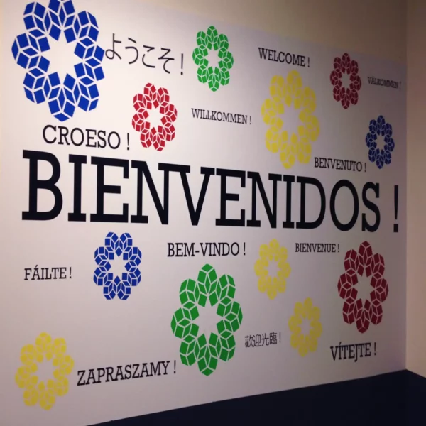 Mactac 8200 colour sign vinyl cut lettering assembled onto a reception wall spelling out "welcome" in a dozen or more languages in different sizes and bright colours.