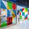 Mactac 9700 Series of self-adhesive decorative translucent colour vinyls have been cut into triangle, circle and square coloured shapes and arranged in an abstract artistic pattern to create this eye-catching backlit retail store front window display.