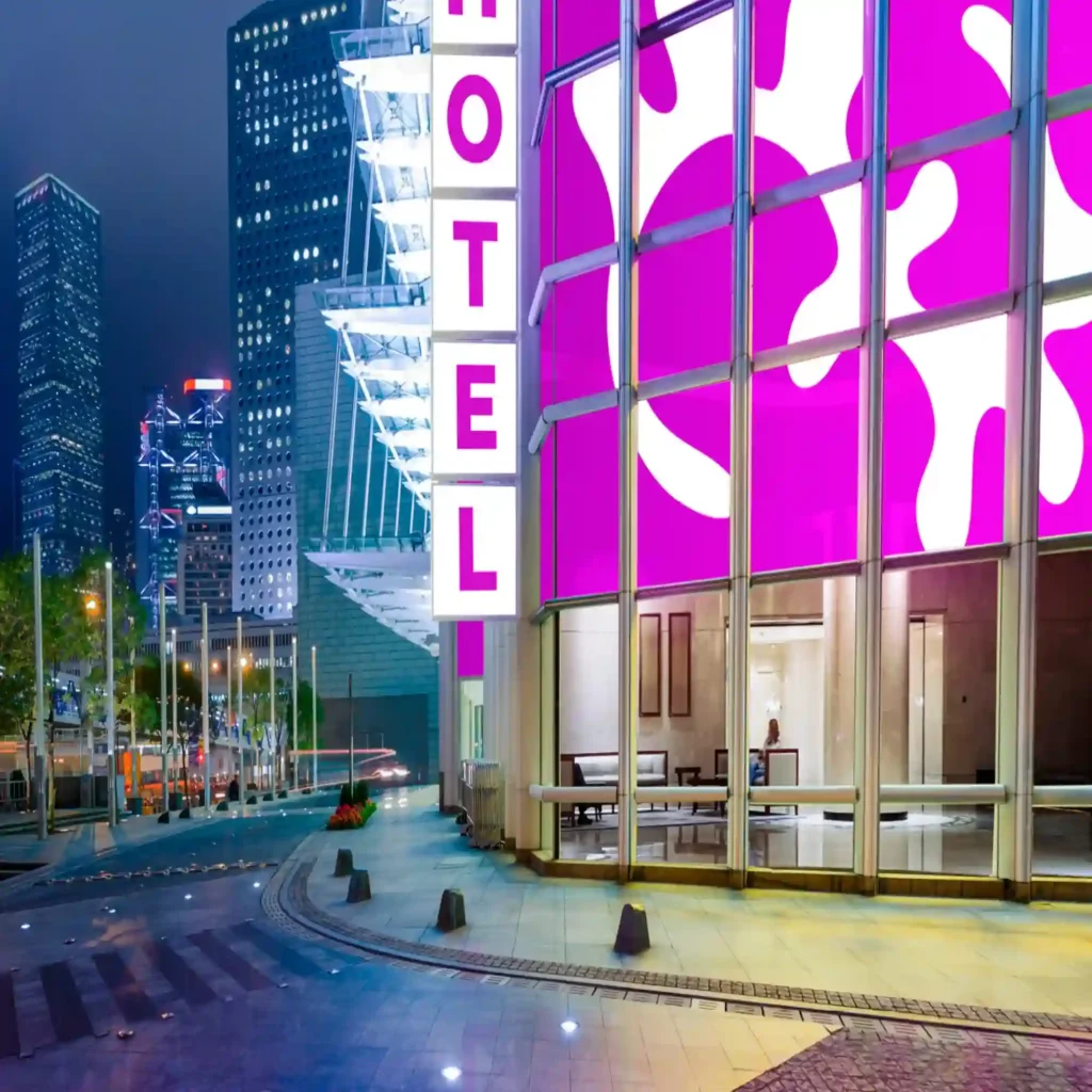 The White and Cyclamen coloured vinyls from Mactac's 9700 Series of polymeric translucent colour films are brightly illuminated in this the coloured backlit signage that covers the large frontage of this hotel display sign and entrance amongst a duskily lit city street.