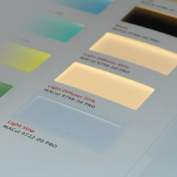 A close-up of Mactac 9722-00 lightstop film on a lightbox with diffuser film samples fading off into the background blur of the photo. With the lightstop film focussed in the foreground of the picture it is easy to see the complete light block this film offers as no light is travelling through this white film for backlit graphics.