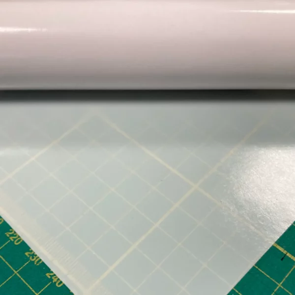 Mactac 9798-60 Light Diffuser film for illuminated signs is rolled out onto a graphics cutting matt with the opacity visible here with 60% show-thru of the cutting matt measurment pattern below the film.