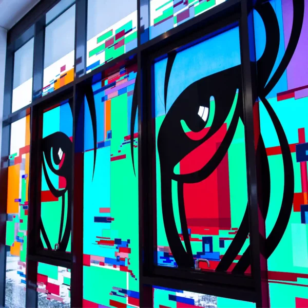 A 'tape-over' style, abstract animalistic image using Mactac 9800 range of pastel sign vinyl shades, in greens, reds, oranges, blues and purple colours which are appied in idividual strips of coloured vinyls to an internal window forming the shape of a Puma's face with black cut-vinyl eyes prominent at the centre of the window design... a work of art!