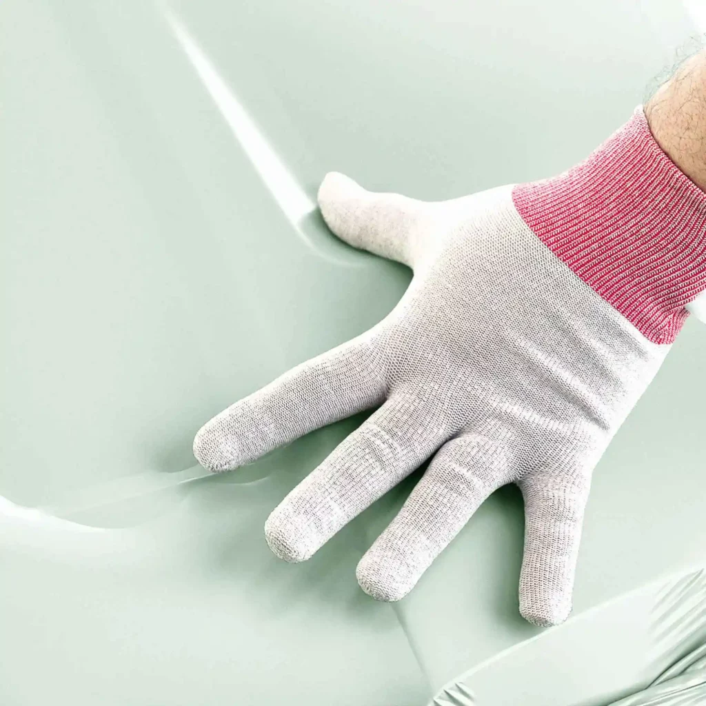 Car wrap glove in an open hand gesture over wrapping film as it is applied onto a vehicle bonnet.
