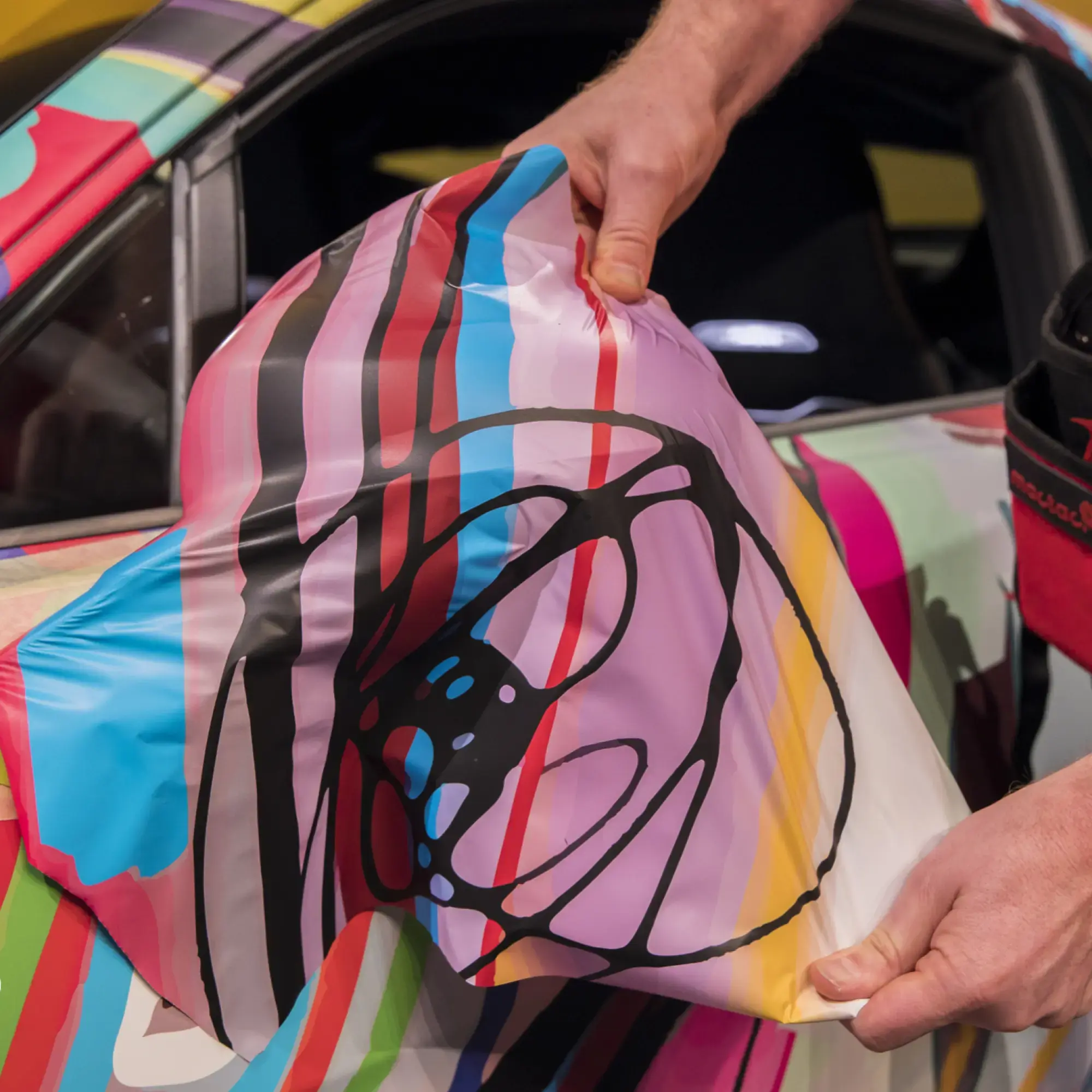 Mactac cast vehicle wrap laminating films for protecting printed car wrapping graphics being conformed around the contours of a wing mirror.