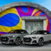Mactac Colourwrap self-adhesive cast conformable vehicle wrap vinyls have transformed these two modern car exteriors with the gloss Light Grey and Ivory coloured films, with the two cars parked in front of an architecturally interesting round roofed bunker building that has also been decorated with brightly coloured wrapping vinyls in a swirling abstract pattern.