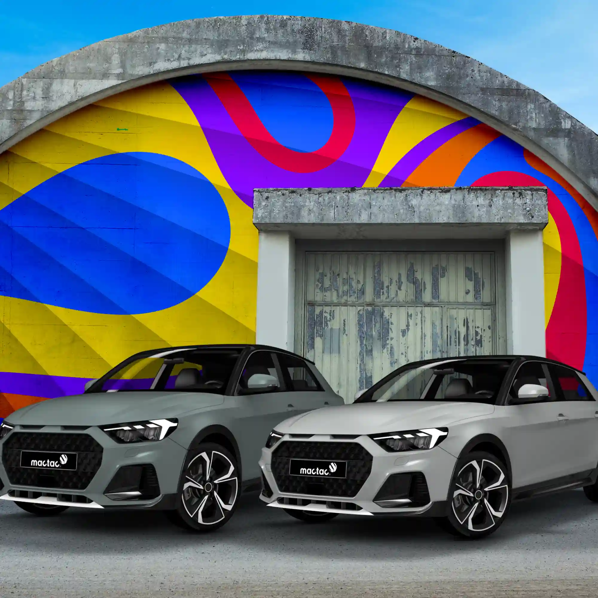 Mactac Colourwrap self-adhesive cast conformable vehicle wrap vinyls have transformed these two modern car exteriors with the gloss Light Grey and Ivory coloured films, with the two cars parked in front of an architecturally interesting round roofed bunker building that has also been decorated with brightly coloured wrapping vinyls in a swirling abstract pattern.