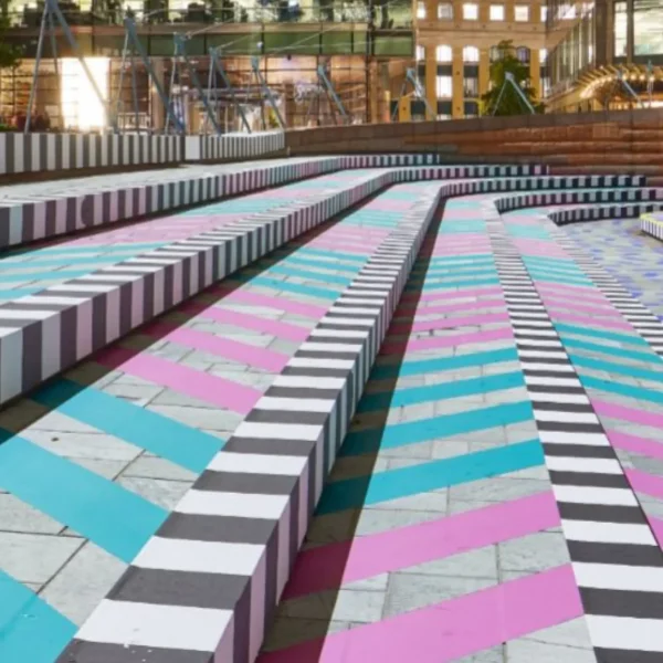 A festival in a park has the floor decorated on the concrete paving with pink, light blue, black and white printed stripe designs