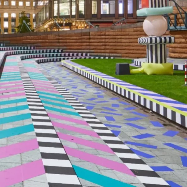 Mactac FloorGrip slip-resistant graphics laminate protecting large scale printed abstract shapes fitted onto concrete paving surfaces at a park festival.