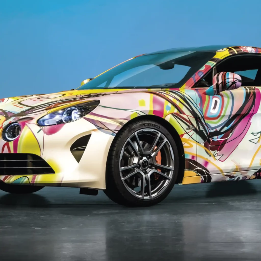 Mactac JT 10700 WG-BFG-XR conformable print wrap film is shown fully applied over all the contours and recesses of this printed, wrapped car with the styled design of a colourful swirling graphic in a hand drawn style.
