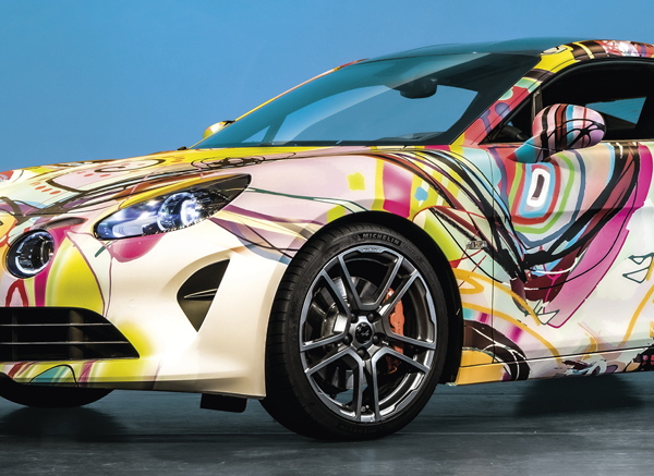 Mactac WG-BFG-XR conformable print wrap film is shown fully applied over all the contours and recesses of this printed, wrapped car with the styled design of a colourful swirling graphic.