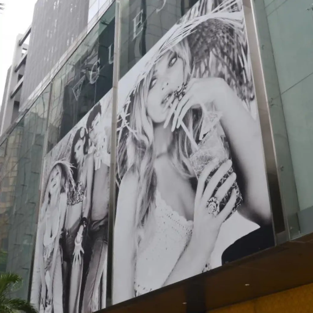 JT 8500 WG-RT monomeric print vinyl printed with a stylish black and white image of summer dressed models. This very large format printed window display graphic decorates the advertising space above a Guess department storefront window display.