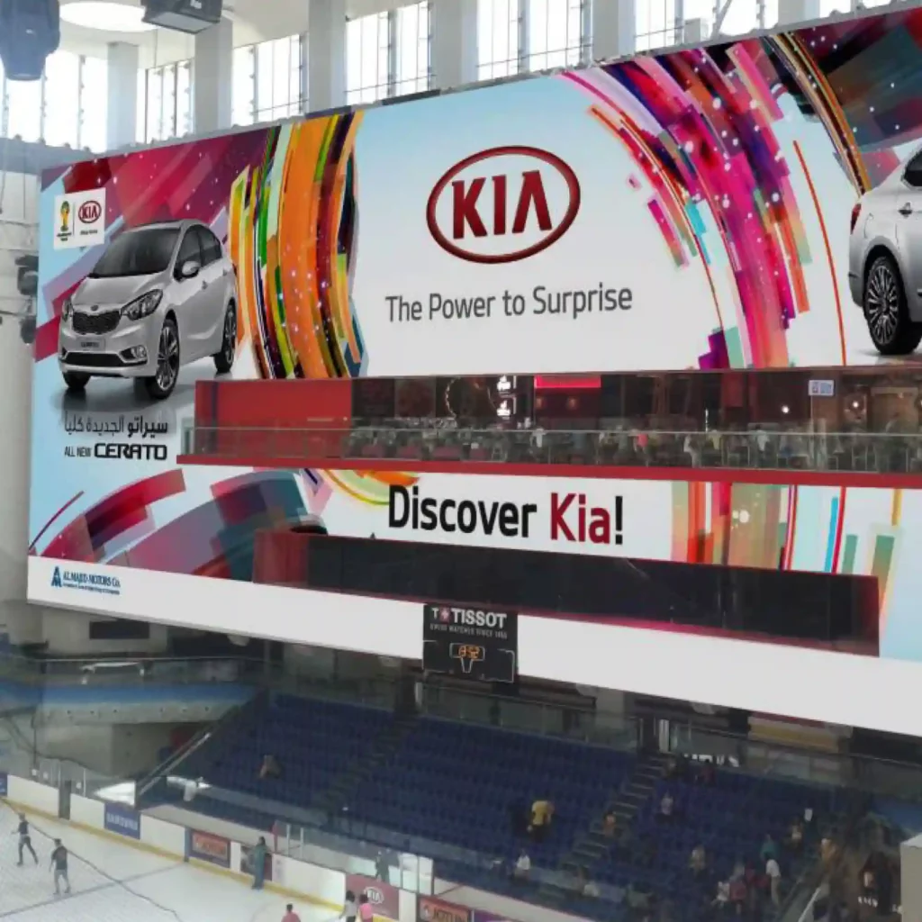 Mactac JT8500 WM-PG matt white monomeric print vinyl with grey opaque adhesive printed with promotional vehicle company branding on a very large format advertising display above one of the spectator seating areas in a sports arena.