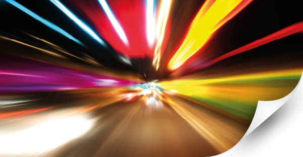 Mactac JT9500 and JT9700 Polymeric Series print vinyls product image: blurred road lights viewed from the front of a speeding car as it speeeds down a motorway with bright streaks of red, yellow, green and orange light streaming outwards from the centre.