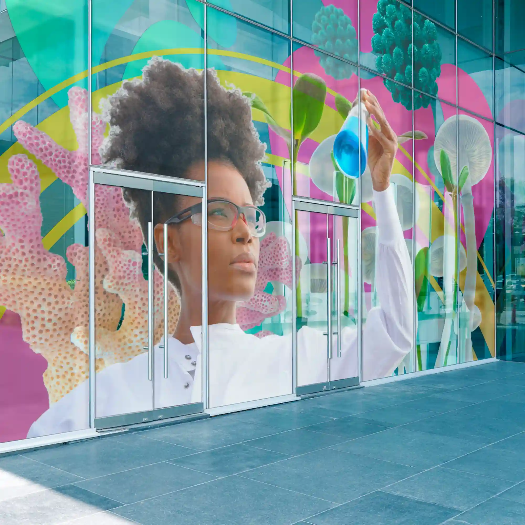 Mactac JT 9700 WT BFT print vinyl offers a frosted, etched glass effect, perfect for creating a professional and modern look for store-fronts, office windows and any glass surfaces. This easy-to-apply, bubble-free self-adhesive print is applied to the entrane windows of a large corprate building and features a science-themed graphic of a woman in laboratory gear inspecting a flask of bright blue fluid.