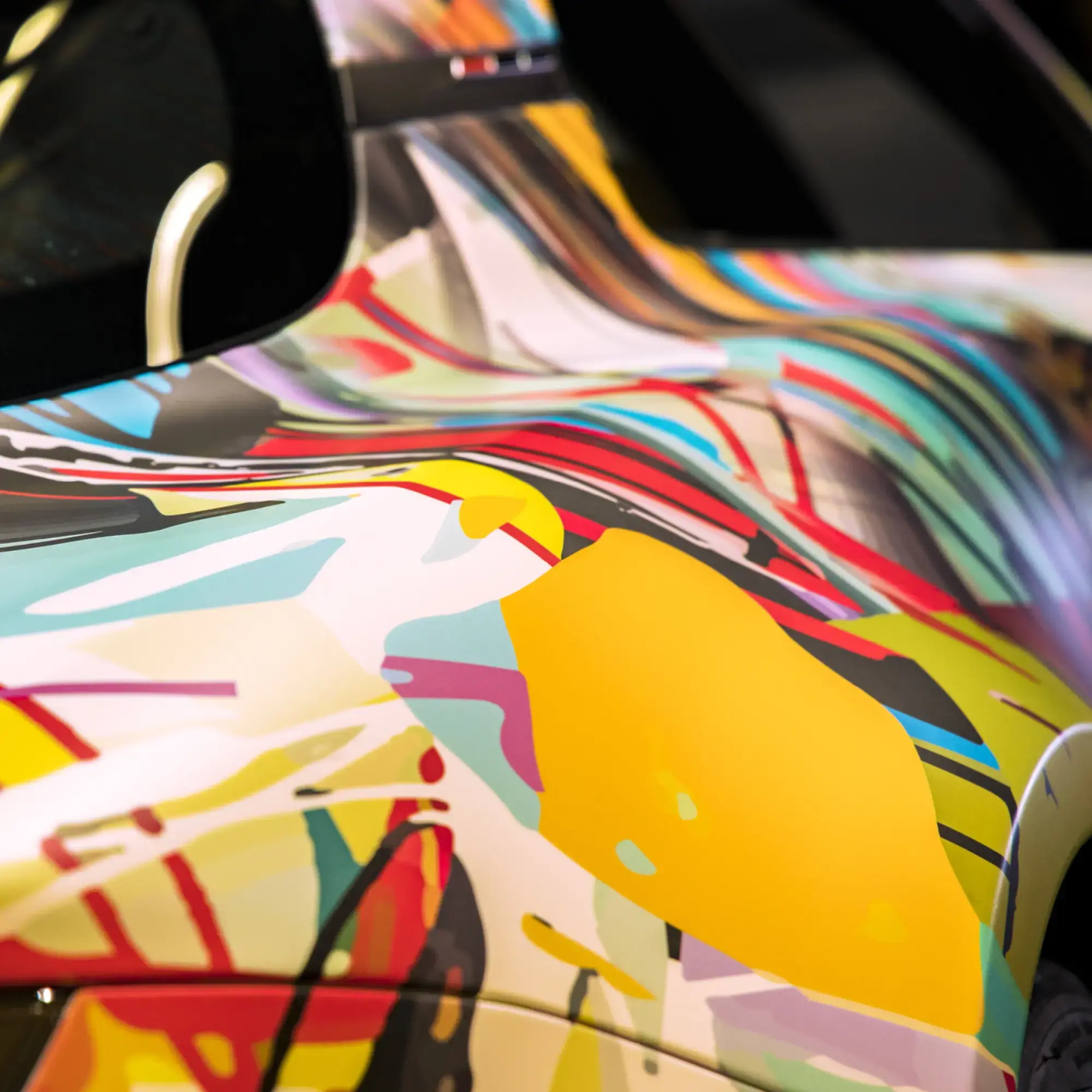 Close-up of a fully wrapped graphic over deep rear side car contours, with the brightly coloured, abstract print image protected by Mactac LF 10700 CG-UV gloss wrapping laminate.