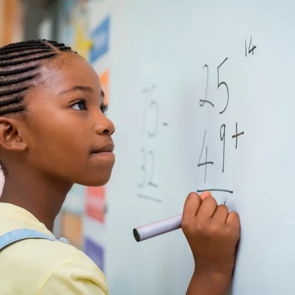 Mactac PG 7034 dry-wipe board film being used to cover a classroom whiteboard and being written on by a young girl doing mathematical sums. This film can also be used as an anti graffiti laminate due to it's similar ink repellent properties where it can be easily cleaned.
