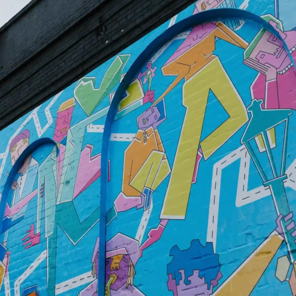 Mactac WW100 conformable print vinyl used for wall graphics on an external painted brick surface, with the fully conformed vinyl being visible as it clings to the contours of the brickwork and mortar beneath the abstract brightly coloured printed design.
