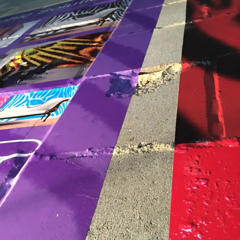 WW100 PRO printed graphics in vibrant purple and red colours showing how the vinyl has conformed into the contours of a bare internal block brick wall over recessed cement lines and rough broken brickwork.