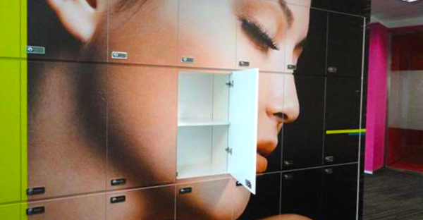 Mactac WW 300 wall print vinyl for difficult to stick to flat, difficult surfaces such as walls, carpets, industricla containers and waste containers and the like - used here in a gym locker room with a large aspirational beauty graphic female face decoration across all of the locker doors.