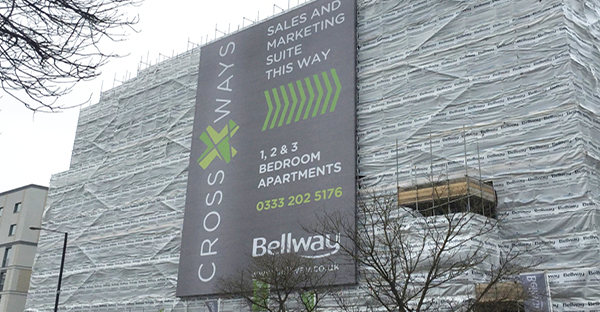 Matt Scrim printable banner material for wide format printed signage, used here on the side of an ultra-large sized construction building site to advertise the marketing suite for available home developments.