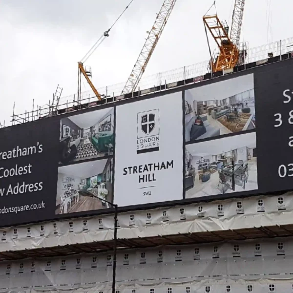 MESH300 building wrap scaffold banner attached to the side of a large new appartments building site with the purpose of highly visible large scale outdoor advertising placement and shielding the general public from unattractive scaffolding and on-site construction in progress.