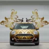 MPI 1104 EA easy to apply, conformable cast print wrapo vinyl print of golden paisly design applied to all the contours of a mini as well as onto the slatted concertina doors behind the vehicle with a printed and cut contour design of some of the pasiley floral design that looks like wings that are protruding from either side of the car.