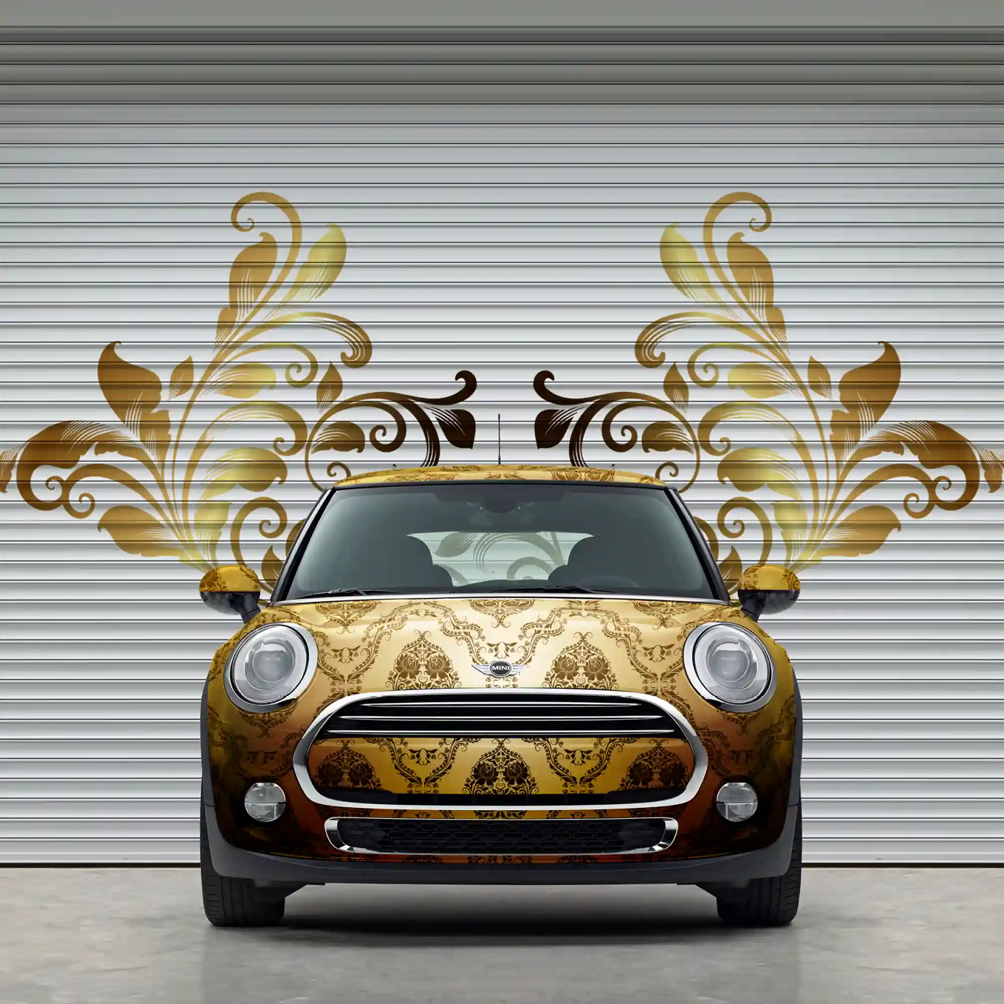 MPI 1104 EA easy to apply, conformable cast print wrapo vinyl print of golden paisly design applied to all the contours of a mini as well as onto the slatted concertina doors behind the vehicle with a printed and cut contour design of some of the pasiley floral design that looks like wings that are protruding from either side of the car.