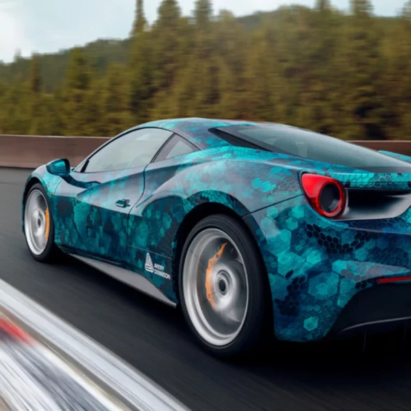 MPI 1105 EA RS, easy apply repositionable and slideable digital cast print wrapping film with a printed blue honeycomb design fitted onto a sportscar is shown speeding around a race track with all the sharp and smooth contours and features of the car accentuated brilliantly by the glossy vinyl and the geometric shape of the design.