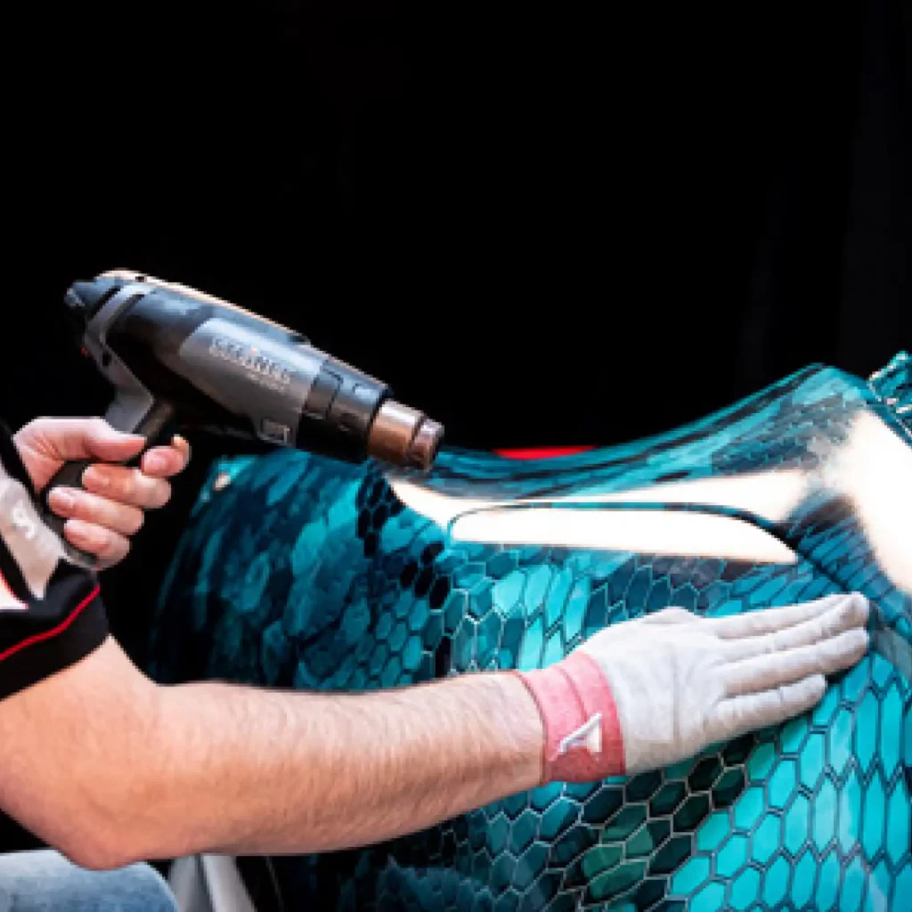 Applying Avery Dennison MPI 1105 EA RS printed wrap vinyl over the smooth and deeply curving contours of a sports car with a stylich, printed blue honeycomb graphic design.