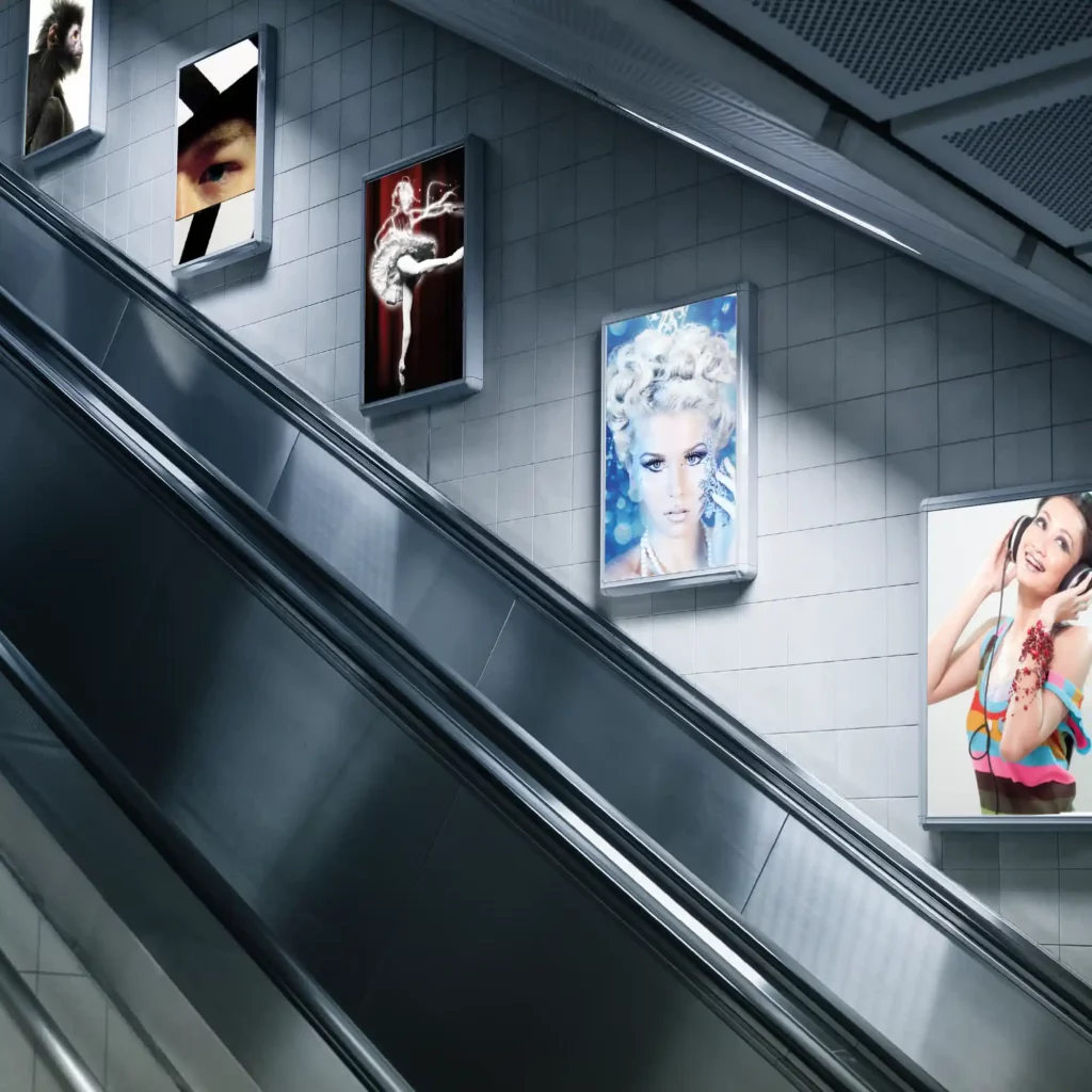 Backlit subway escalator wall posters printed on non-adhesive polyester print film, illuminated for vibrant visual impact.