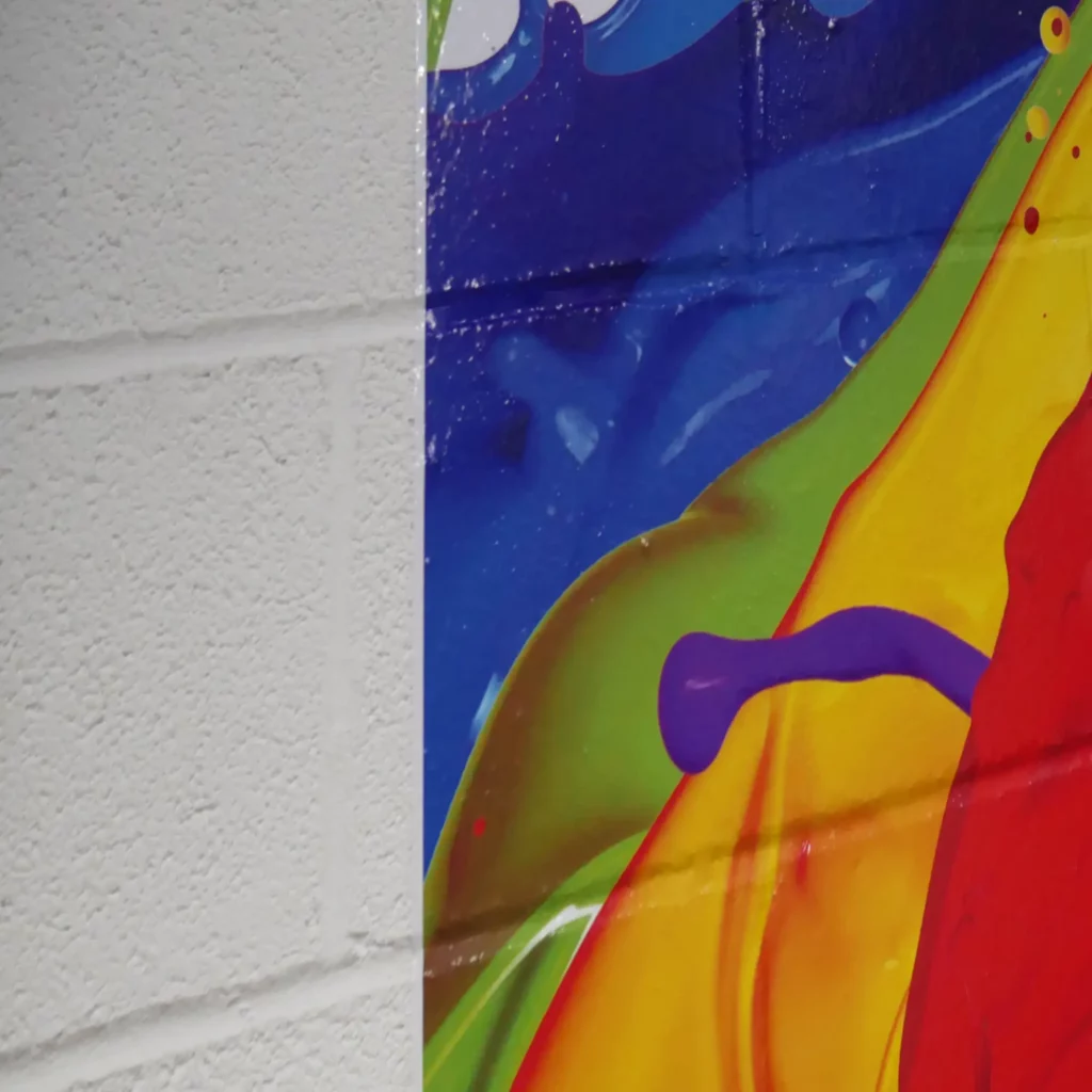 NU-COAT 'M' Series of monomeric print vinyls feature ultra grab self-adhesive for sticking printed graphics onto surfaces which require extra adhesion power, stuck onto substrates such as this painted breeze block wall shown in this photograph.