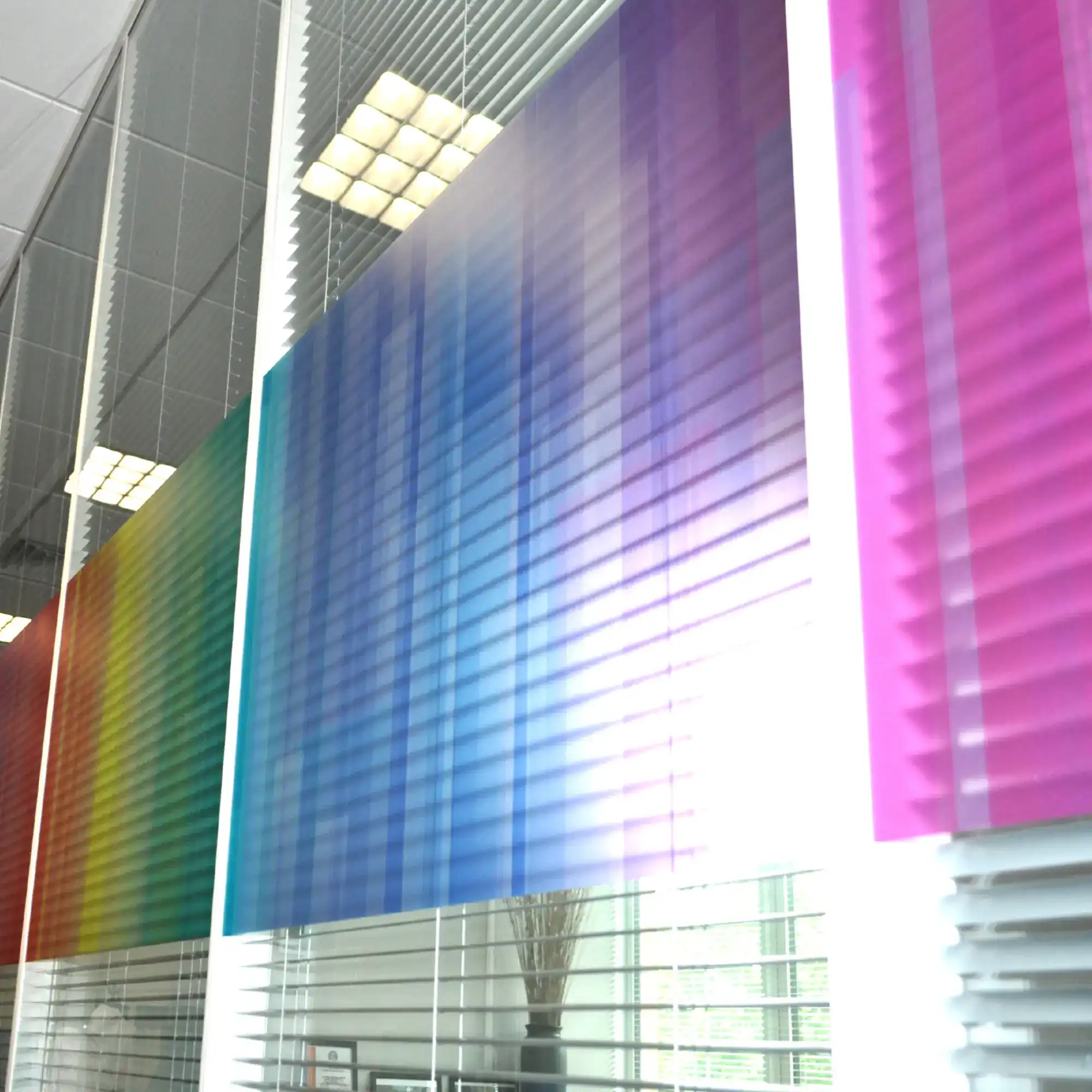 NU-COAT P65-W silver crystal finish, self-adhesive wide-format window film is printed with a bright and colourful rainbow pattern using a digital inkjet printer and has been applied to the outside of an internal conference room set of glass partition windows, adding decorative colour and obscurity/privacy for the room occupants as the film blocks out most of what is visible behind the applied vinyl.