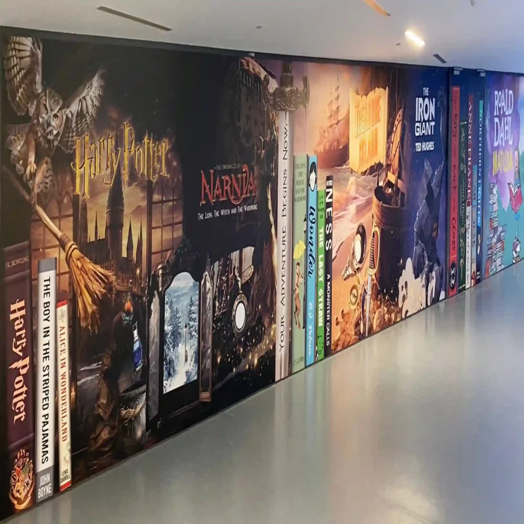 NU-COAT polymeric HighGRAB print vinyls printable with digital inks for more difficult to stick to substrates that require a little bit stronger adhesion to the surface, such as used here for this school corridor wall graphic printed with images of book covers and spines as it sitting on a bookshelf but human sized to fit the entire wall.
