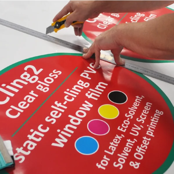 Trimming out imposed, printed circular signs that are branded with crisp, colourful NU-COAT clear gloss static cling window print vinyl graphics.