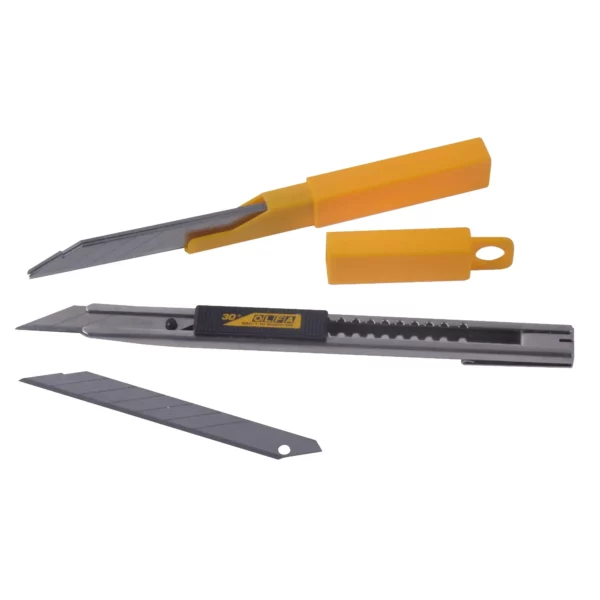 OLFA SAC-1 retractable snap-off knife, a slimline stainless steel construction with retractable blade detailing the mechanism for retracting the 30° blade at the centre of the photo. Also included in the pic are the replacment blades in the blade protection case and an individual blade - the objects are fanned out in a semi-oval shape.