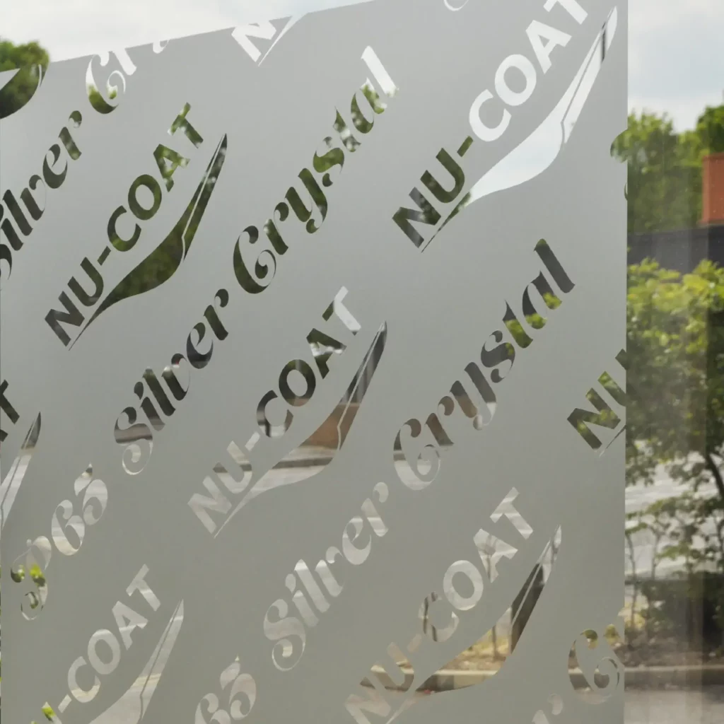P65-W Silver Crystal self-adhesive window film has been plotter cut and the unwanted cut-vinyl has been removed/weeded-out, so the words "Silver Crystal" and the "NU-COAT" logo are removed from the film leaving an intentional gap so you can see through the window to the outside while the film that was left non-weeded is stuck onto the glass surface, creating an up-market etch-glass effect decorative window graphic that provides both impressive obscurity/privacy and a neat looking signage graphic.
