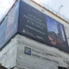 PF550 print branded building wrap scaffold banner attached to the side of a large city appartment construction site, offering the dual-purpose of high-impact outdoor advertising placement as well as shielding the public from unsightly scaffolding and on-site building work in progress.
