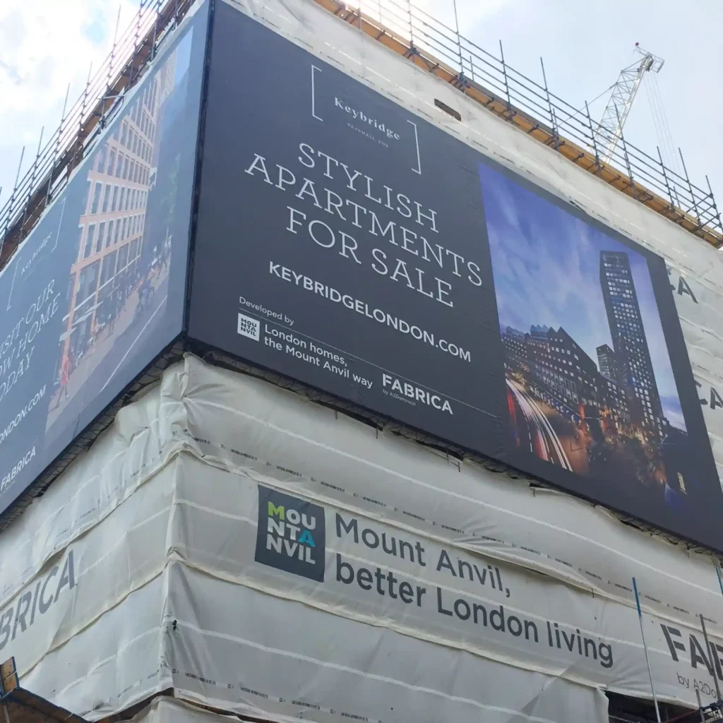 PF550 print branded building wrap scaffold banner attached to the side of a large city appartment construction site, offering the dual-purpose of high-impact outdoor advertising placement as well as shielding the public from unsightly scaffolding and on-site building work in progress.